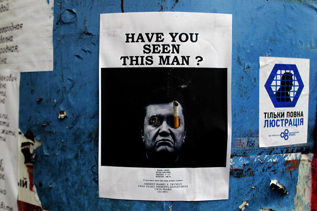 A poster with a photo of fugitive Ukrainian President Viktor Yanukovich, who fled the capital Kiev and went into hiding after months of protests against his government, is seen fixed onto a barricade in central Kiev 