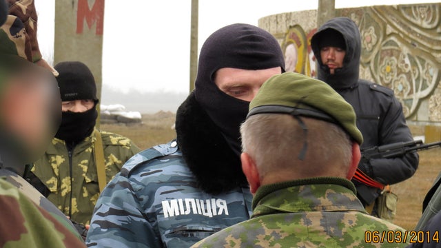 Two members of an Organisation for Security and Cooperation in Europe (OSCE) military observer mission (facing away from camera) are stopped at the Crimean border by unknonw armed men  