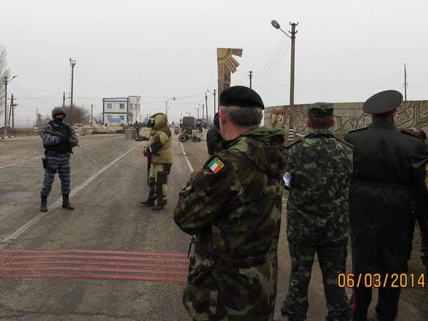 Members of an Organisation for Security and Cooperation in Europe (OSCE) military observer mission (at right, facing away from camera) are stopped at the Crimean border by unknonw armed men 