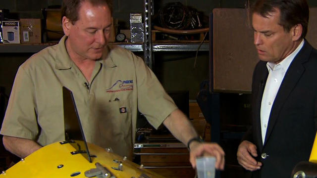 Curt Newport, left, an airplane search and recovery operations expert, explains airplane recovery technology to CBS News' Chip Reid. 