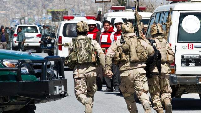 Emergency medical personnel wearing bullet proof vests watch as Afghan Special Forces troops rush toward an Afghan election commission office during an attack by militants in Kabul 
