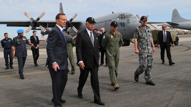 Australia's Prime Minister Tony Abbott, foreground left, and Malaysia Prime Minister Najib Razak, foreground second from left, walk on the tarmac at Royal Australian Air Force Base Pearce in Perth 