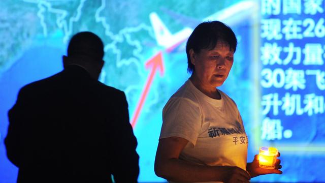 A Chinese relativeof passengers on the missing Malaysia Airlines flight MH370 holds a candle as she takes part in a prayer service at the Metro Park Hotel in Beijing 