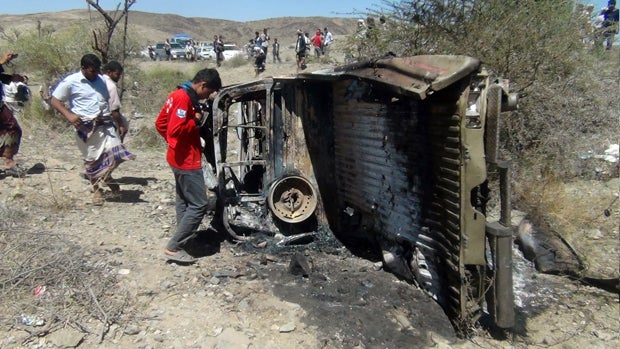 People inspect the wreckage of a car hit by an air strike in the central Yemeni province of al-Bayda April 19, 2014. 