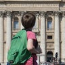 A boy looks towards tapestries showing portraits of late Popes John Paul II (L) and John XXIII on the balconies of St. Peter's basilica 