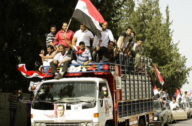 Syrian refugees ride on a truck adorned with pictures of Syrian President Bashar Assad near the southern city of Sidon, May 28, 2014, on the way to the Syrian embassy to cast their ballots in the Syrian presidential elections 