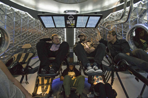 SpaceX CEO Elon Musk (L) sits with guests inside the Dragon V2 spacecraft after it was unveiled in Hawthorne 