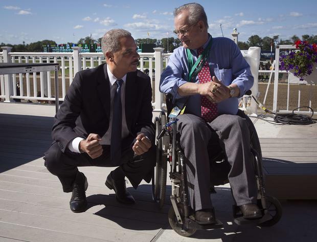 Attorney General Eric Holder, left, kneels down to speak with former jockey Ron Turcotte before the 146th running of the 2014 Belmont Stakes in Elmont, New York, June 7, 2014.  Turcotte rode famed horse Secretariat to the Triple Crown and Holder was sitti 