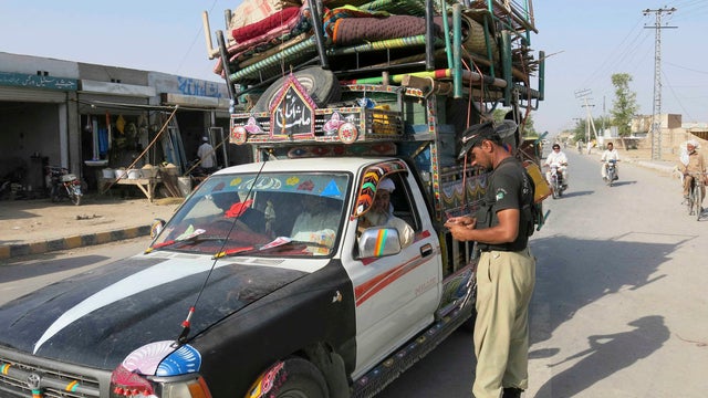 A policeman checks an identification card of residents travelling with their belongings on a vehicle, fleeing a military offensive against Pakistani militants in North Waziristan 