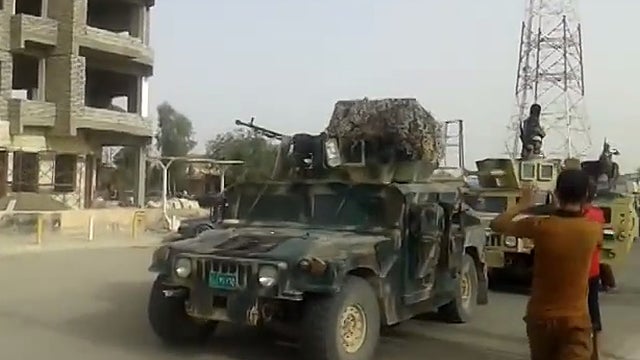 ISIS militants driving stolen Iraqi military vehicles through the northern city of Baiji. 