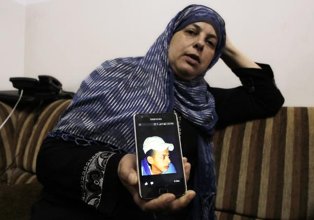 Suha, mother of Mohammed Abu Khudair, shows a picture of her son on her mobile phone at their home in Shuafat 