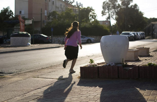 An Israeli girl runs as a siren sounds warning of incoming rockets in the southern city of Ashkelon 