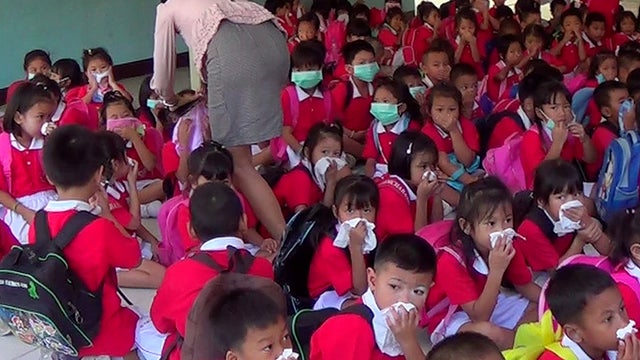 A teacher, left, helps her children to put on masks after a chemical leak 