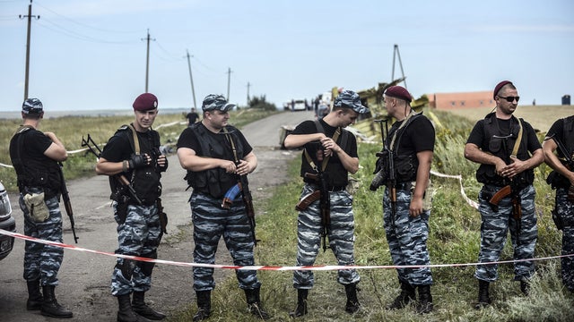Armed pro-Russian separatists stand guard in front of the crash site of Malaysia Airlines Flight 17 near the village of Grabovo 