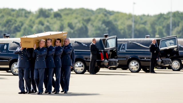 Dutch military personnel carry a coffin containing the remains of victims of Malaysia Airlines Flight 17 plane crash to a waiting hearse at the airbase in Eindhoven 