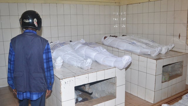 A man stands in front of bodies at a morgue in Conakry, Guinea, July 30, 2014, a day after at least 33 people, including children, died in a stampede  