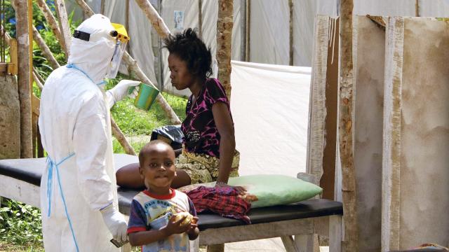 A health worker offers water to a woman with Ebola virus disease (EVD) at a treatment center for infected persons in Kenema Government Hospita 