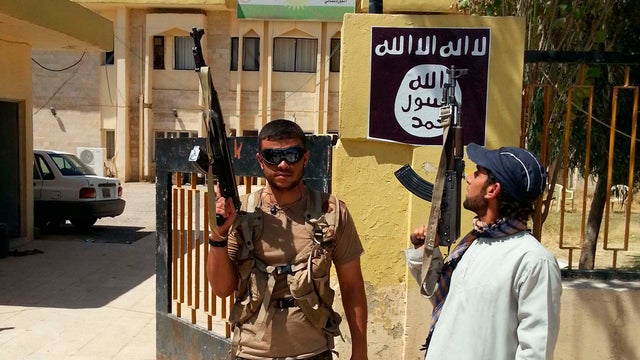 ISIS militants stand guard after controlling a headquarters of the Kurdistan Democratic Party (KDP) in the Christian town of Bartella 