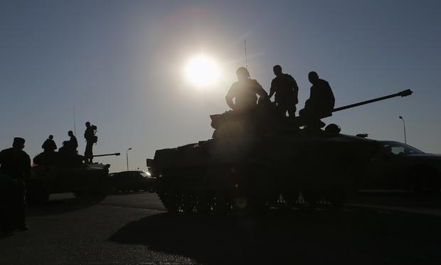 Russian military personnel sit atop armoured vehicles outside Kamensk-Shakhtinsky, in Russia's Rostov region 