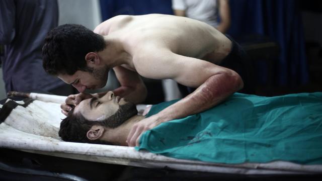 A Syrian man kisses the body of his brother who was reportedly killed in a Syrian army airstrike 