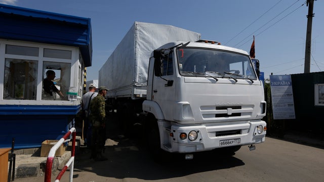 Ukrainian border guards look at the first truck in a Russian aid convoy as it passes the border post at Izvaryne 