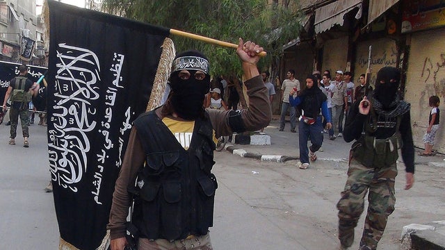 Fighters from the al Qaeda group in Syria, al-Nusra Front, wave their movement's flag as they parade at the Yarmuk Palestinian refugee camp 