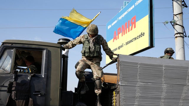 A soldier of Ukrainian self-defense battalion "Azov" jumps out of a truck as he arrives at a check point in the southern coastal town of Mariupo 