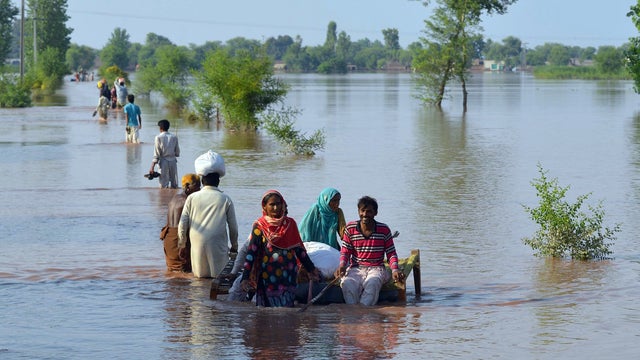 Pakistani residents wade through floodwaters at a village in Jhang, in the central Punjab province 