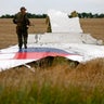 An armed pro-Russian separatist stands on part of the wreckage of the Malaysia Airlines Boeing 777 plane July 17, 2014, after it crashed near the settlement of Grabovo in the Donetsk region. 