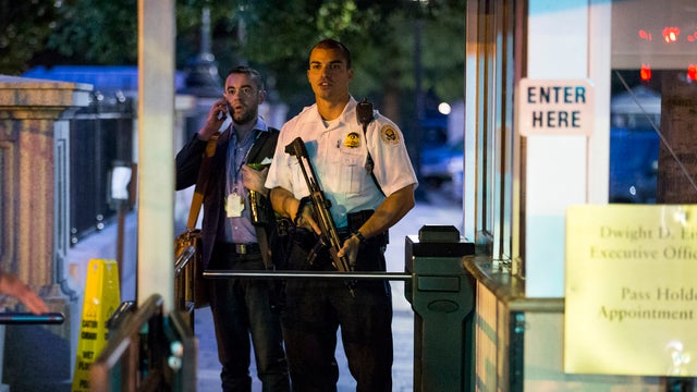 A Secret Service police officer holds a weapon as he stands near an entrance to the White House complex during an evacuation minutes after President Obama departed Washington for Camp David aboard Marine One Sept. 19, 2014. 