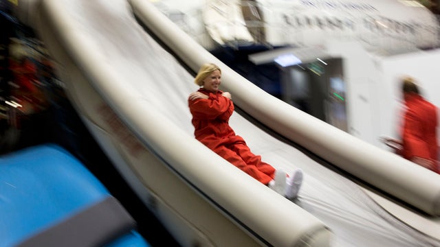 A participant slides down an escape slide during a British Airways flight safety course at the airline's Cranebank training facility near Heathrow Airport in London Sept. 10, 2014. 
