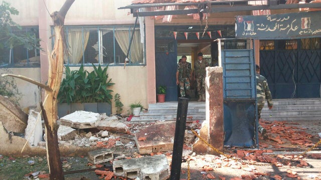 Soldiers are seen around wreckage in a school after twin suicide bombs in Homs 