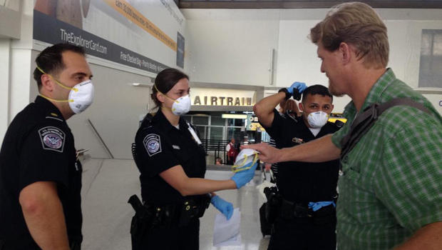 U.S. customs agents hand out surgical masks at Newark Liberty International Airport Oct. 4, 2014, after the Centers for Disease Control and Prevention removed a passenger from an international flight in Newark, N.J. 