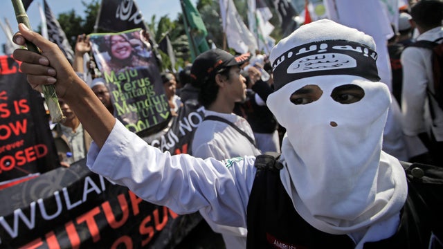 A Muslim man wears a headband showing ISIS' symbol during a protest calling for the closure of a local prostitution complex in Surabaya Indonesia 