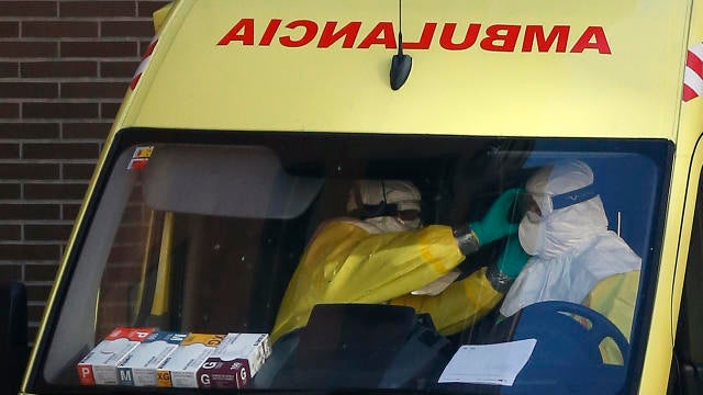 An ambulance crew adjusts their goggles outside the entrance of the apartment building of the nurse who contracted Ebola in Alcorcon, outside Madrid, Oct. 8, 2014. 