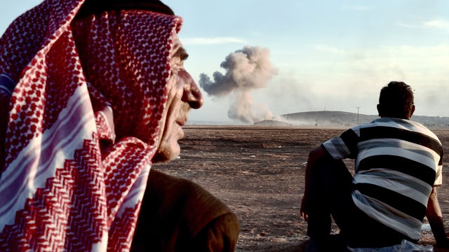 People in the Turkish border village of Mursitpinar watch smoke rising from the Syrian town of Kobani after an airstrike 
