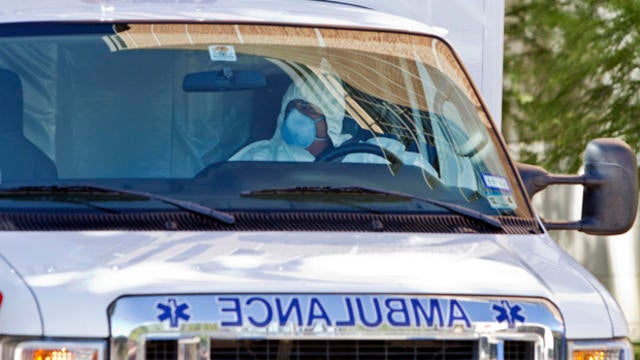 An ambulance driver wearing a protective suit escorts Amber Joy Vinson, not shown, the second health worker to be infected with the Ebola virus at Texas Health Presbyterian Hospital, to the airport in Dallas Oct. 15, 2014. 