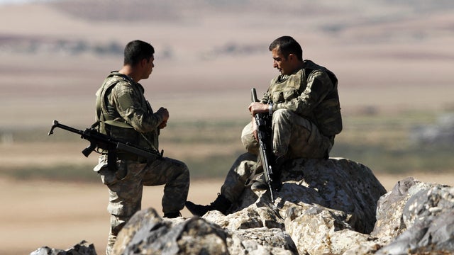  Turkish soldiers watch the Syrian town of Kobani from a hil 