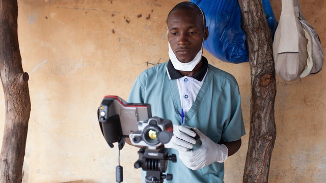 A health worker checks the temperature of a baby entering Mali from Guinea at the border in Kouremale 