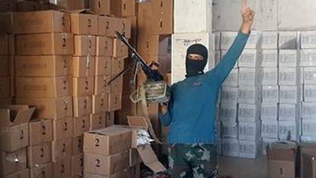 ​A militant from the Nusra Front gestures in front of a large store of humanitarian aid seized by the group in Idlib province.  