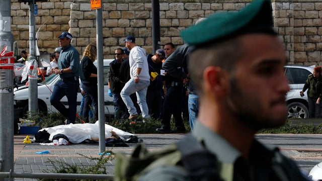 The covered body of a Palestinian motorist lies on the tracks of the light railway in Jerusalem  