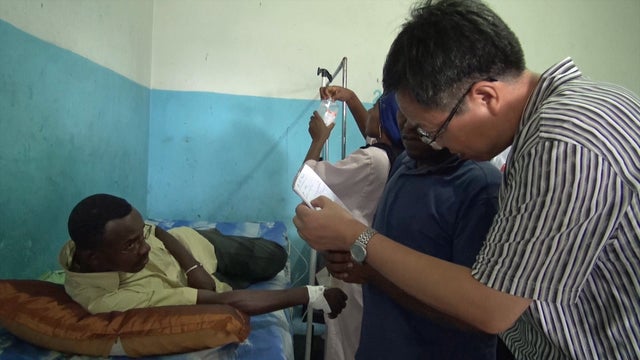 ​Chinese malaria researcher Song Jianping looks at medical charts for a patient in the Comoros 