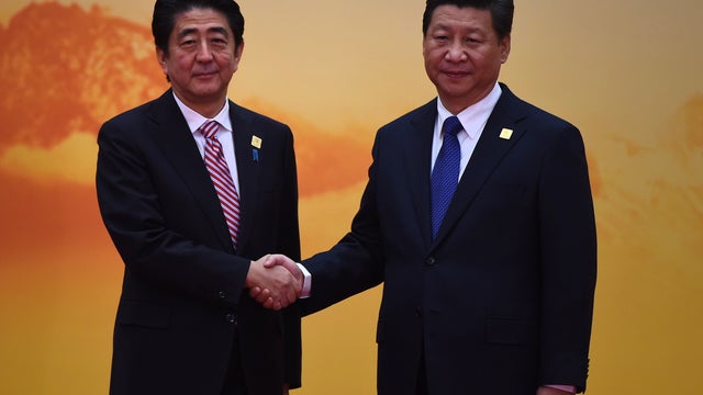 Japan's Prime Minister Shinzo Abe (L) shakes hands with China's President Xi Jinping  