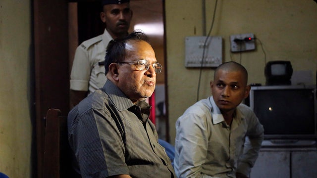 R.K. Gupta (L), a doctor who performed sterlization surgeries at a government mass sterilization "camp," sits at a police station 