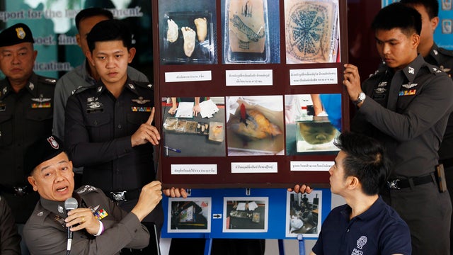 Policemen show pictures of body parts found in parcels as they address reporters in Bangkok 