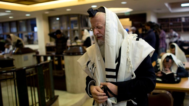 Jewish worshipers pray at a synagogue in Jerusalem where two Palestinian militants killed four rabbis and a policeman 