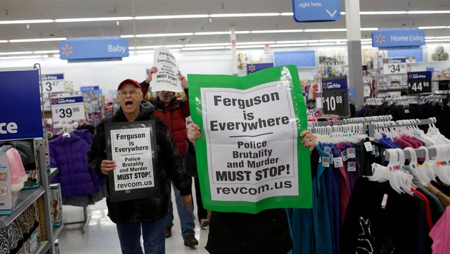 Demonstrators protesting the shooting death of Michael Brown hold signs as they walk through a local Wal-Mart store on Black Friday, Nov. 28, 2014, near Ferguson, Missouri.