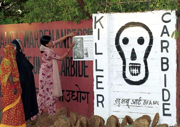 Women place posters along the walls of the closed-down Union Carbide plant in Bhopal, India, to mark the 15th anniversary of the world's worst industrial accident, Dec. 1, 1999. 