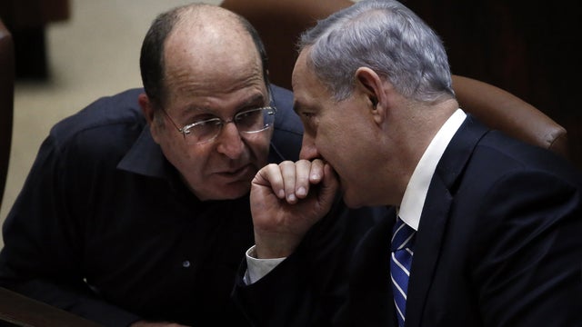 Israeli Prime Minister Benjamin Netanyahu (R) discusses with Israeli Defense minister Moshe Yaalon before the ultimate vote to dissolve the Israeli Parliament at the Knesset in Jerusalem 