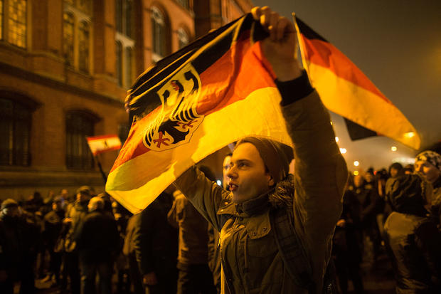 A supporter of the PEGIDA movement holds a flag while supporters gather for a march in their first Berlin demonstration, which they have dubbed "Baergida," 